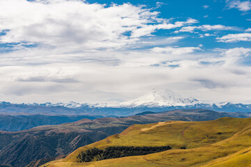 Big mountain Elbrus against the blue sky. View from a large plateau and steep cliffs.