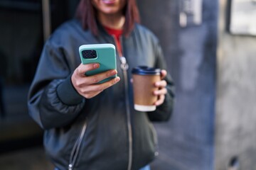 Young beautiful hispanic woman using smartphone drinking coffee at street