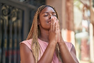 African american woman praying with closed eyes at street