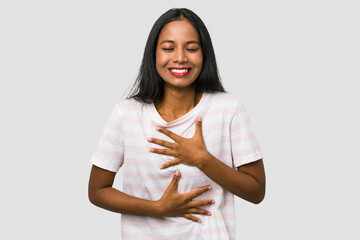 Obraz premium Young Indian woman cut out isolated on white background laughs happily and has fun keeping hands on stomach.