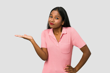 Young Indian woman cut out isolated on white background showing a copy space on a palm and holding...