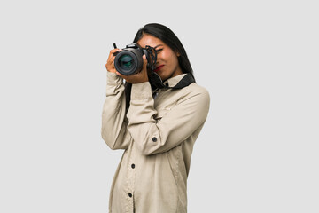 Young Indian photographer woman holding a professional camera isolated - obrazy, fototapety, plakaty