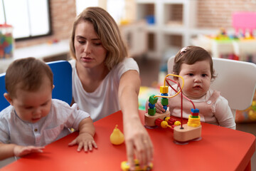 Teacher and preschool students playing with toys sitting on table at kindergarten
