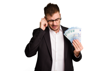 Young business caucasian man holding euro banknotes isolated cut out covering ears with hands.