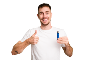 Young caucasian man holding a vaporizer cut out isolated smiling and raising thumb up