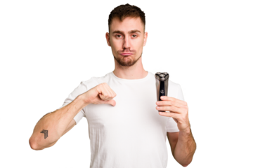Young man holding a shaving machine cut out isolated feels proud and self confident, example to follow.