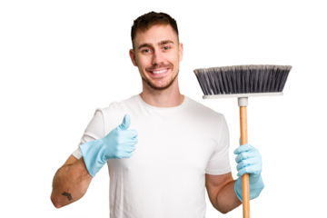 Young man holding a broom to clean his house cut out isolated smiling and raising thumb up