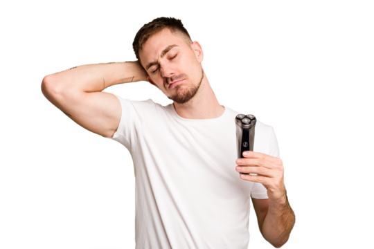 Young man holding a shaving machine cut out isolated touching back of head, thinking and making a choice.
