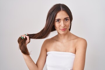 Young hispanic woman holding hair with hand thinking attitude and sober expression looking self confident