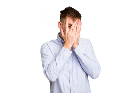 Young caucasian man cut out isolated blink through fingers frightened and nervous.