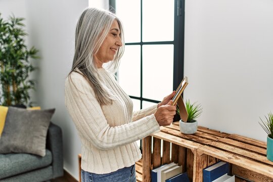 Middle age grey-haired woman smiling confident looking photo at home