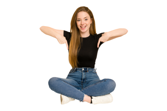 Young redhead woman sitting on the floor cut out isolated points down with fingers, positive feeling.