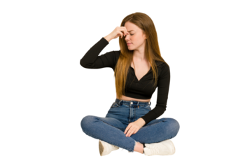 Young redhead woman sitting on the floor cut out isolated showing thumb down, disappointment concept.