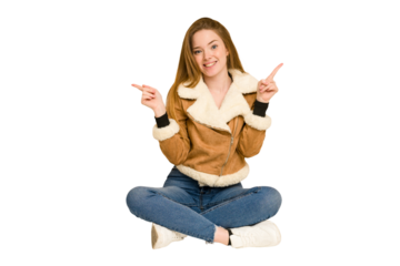 Young redhead woman sitting on the floor cut out isolated having a neck pain due to stress, massaging and touching it with hand.