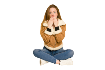 Young redhead woman sitting on the floor cut out isolated praying, showing devotion, religious person looking for divine inspiration.