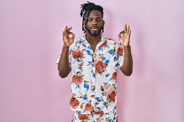 African man with dreadlocks wearing summer shirt over pink background relax and smiling with eyes closed doing meditation gesture with fingers. yoga concept.