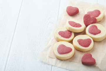 Valentines day cookies. Shortbread cookies inside a sweet red heart on parchment paper on white background. Mothers day. Womans day. Sweet holidays baking. Top view.