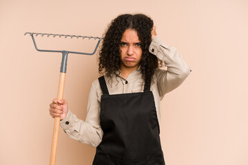Young african american gardener woman holding a rake isolated being shocked, she has remembered important meeting.