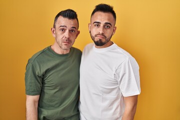 Homosexual couple standing over yellow background depressed and worry for distress, crying angry and afraid. sad expression.