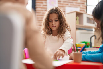 Two kids preschool students sitting on table drawing on paper at kindergarten
