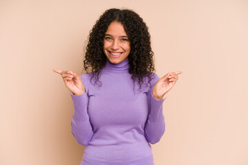 Young african american curly woman isolated pointing to different copy spaces, choosing one of them, showing with finger.