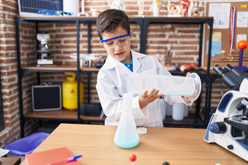 Fototapeta na wymiar Adorable hispanic boy student pouring liquid on test tube at laboratory classroom