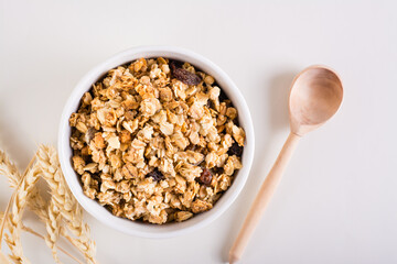 Baked granola in a bowl, wooden spoon and ears on the table. Healthy breakfast. Top view.