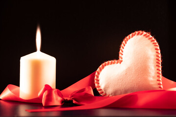 	
Composition pour la Saint-Valentin avec un cœur blanc et rouge et une bougie.	