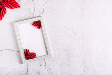 Blank photo frame and DIY paper hearts and leaves on plaster. Home decor. Copy space