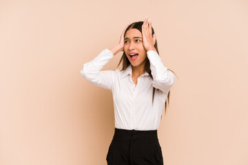 Young colombian woman isolated on beige background covering ears with hands trying not to hear too...