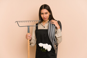 Young colombian gardener woman isolated on beige background