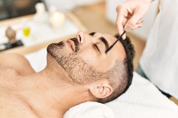 Fototapeta na wymiar Young hispanic man having eyebrows treatment at beauty center