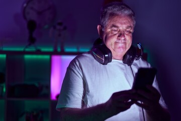 Middle age grey-haired man streamer using smartphone at gaming room