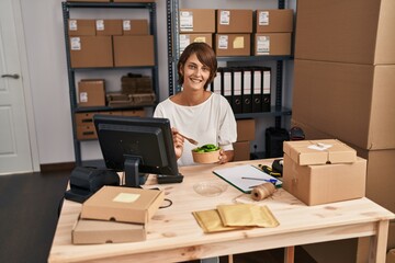 Young beautiful hispanic woman ecommerce business worker eating salad at office