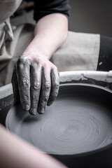 Women working at pottery wheel, creating dishes. The dirty hands of the potter in the clay and on the wheel. Creation. - 561608654
