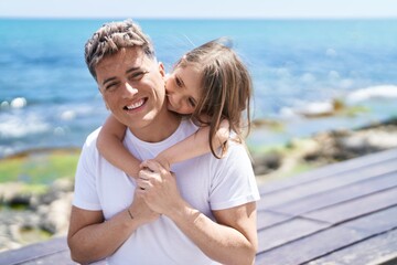 Father and daughter smiling confident standing together at seaside