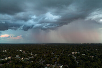 Fototapeta premium Dark stormy clouds forming on gloomy sky before heavy rainfall over suburban town area