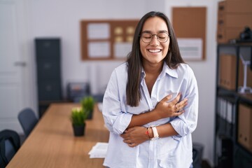 Young hispanic woman at the office smiling and laughing hard out loud because funny crazy joke with hands on body.