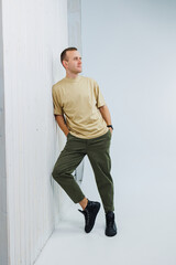 A young handsome man in casual clothes poses on a white background in the studio