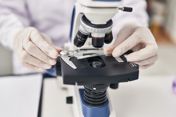 Fototapeta na wymiar Middle age hispanic woman wearing scientist uniform using microscope at laboratory