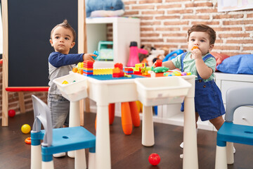 Two kids playing with construction blocks standing at kindergarten