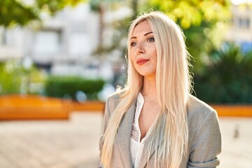 Plakat Young blonde woman standing with relaxed expression at park