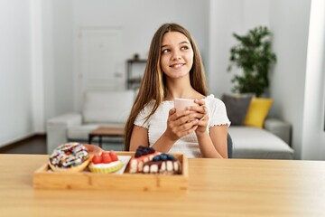 Adorable girl having breakfast sitting on table at home