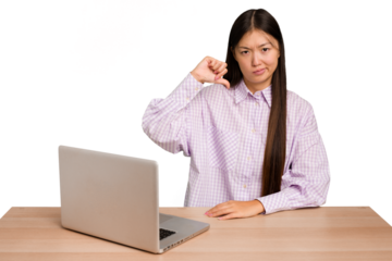 Young student asian woman in a workplace with a laptop isolated showing thumb down, disappointment concept.