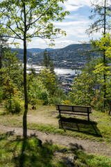 Landscape with an empty park bench and view from park hill to the river Drammenselva and the town Drammen