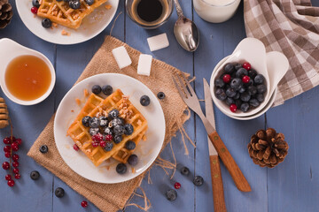 Fototapeta na wymiar Waffles with red currant and blueberries on white dish.