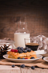 Waffles with red currant and blueberries on white dish.