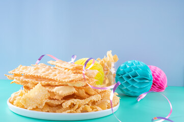 Sfrappole or chiachiere or angel wings on a bright blue background. Italian Carnival and TYPICAL food. Traditional sweet crisp pastry deep-fried and sprinkled . Copy space