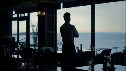 Pensive man silhouette standing restaurant hall alone. Business success concept