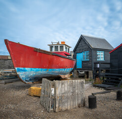 Fototapeta na wymiar Southwold Harbour on the River Blyth in Suffolk, an old fishing boat in dry dock in front of a wooden hut